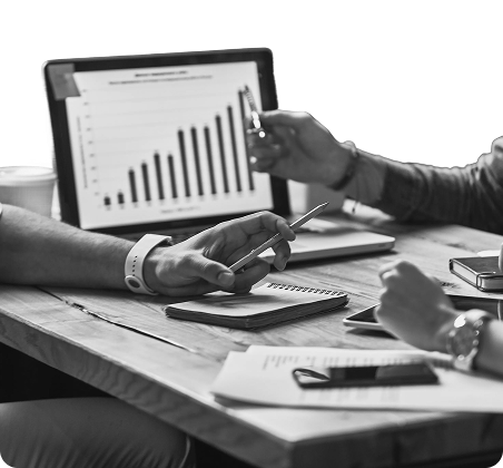 Team collaborating around a table with laptop displaying analytics